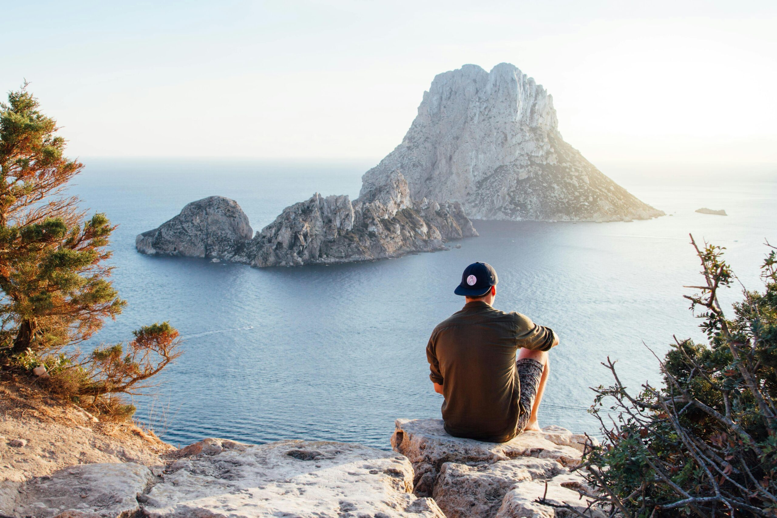 man sitting over a rock mountain gazing over the see